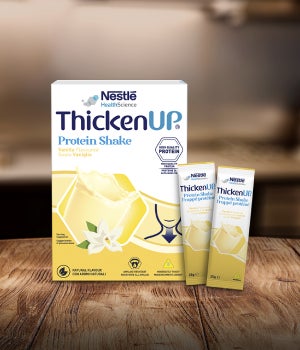 Integratore proteico Nestlé ThickenUp al gusto vaniglia su tavolo di legno.